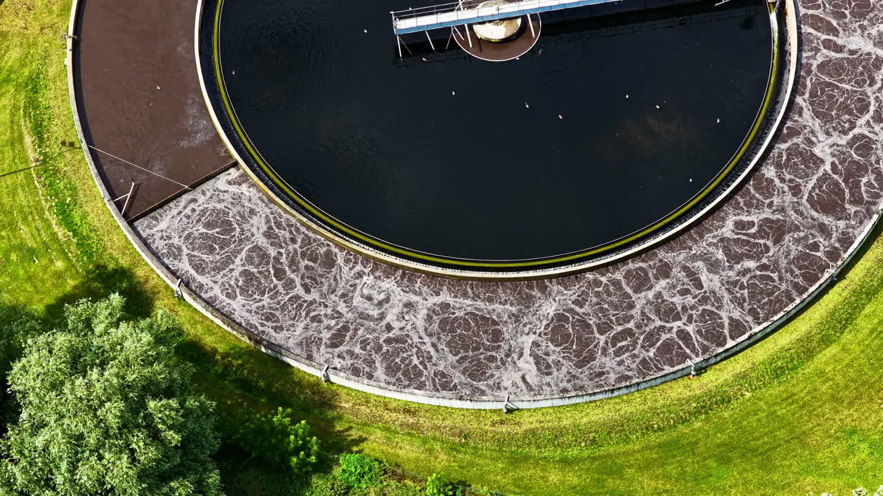Top down aerial of churning wastewater vat in treatment facility showing swirling patterns