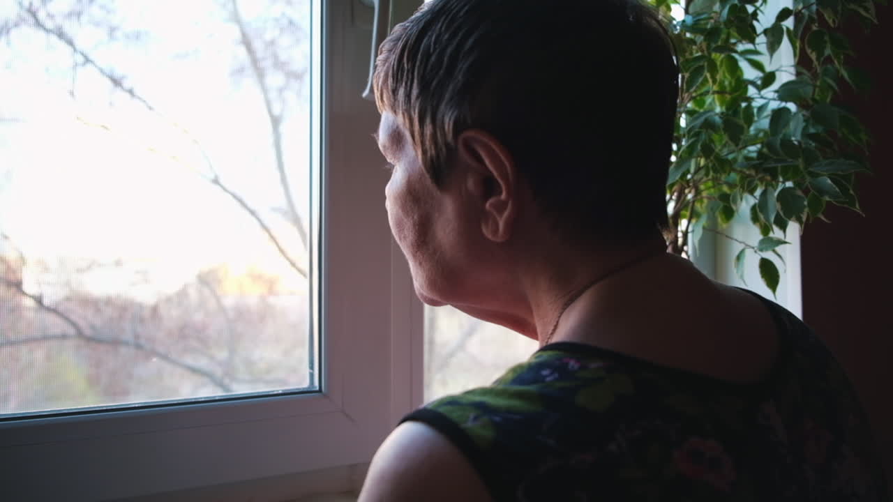 창문 밖을 바라보는 고령 여성