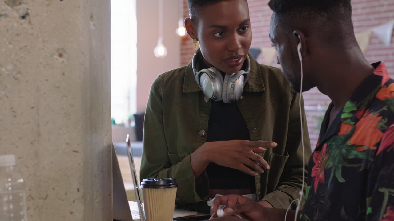 giovani uomini d'affari afroamericani che fanno brainstorming lavorando insieme condividendo idee indossando cuffie ascoltando musica in un ufficio alla moda