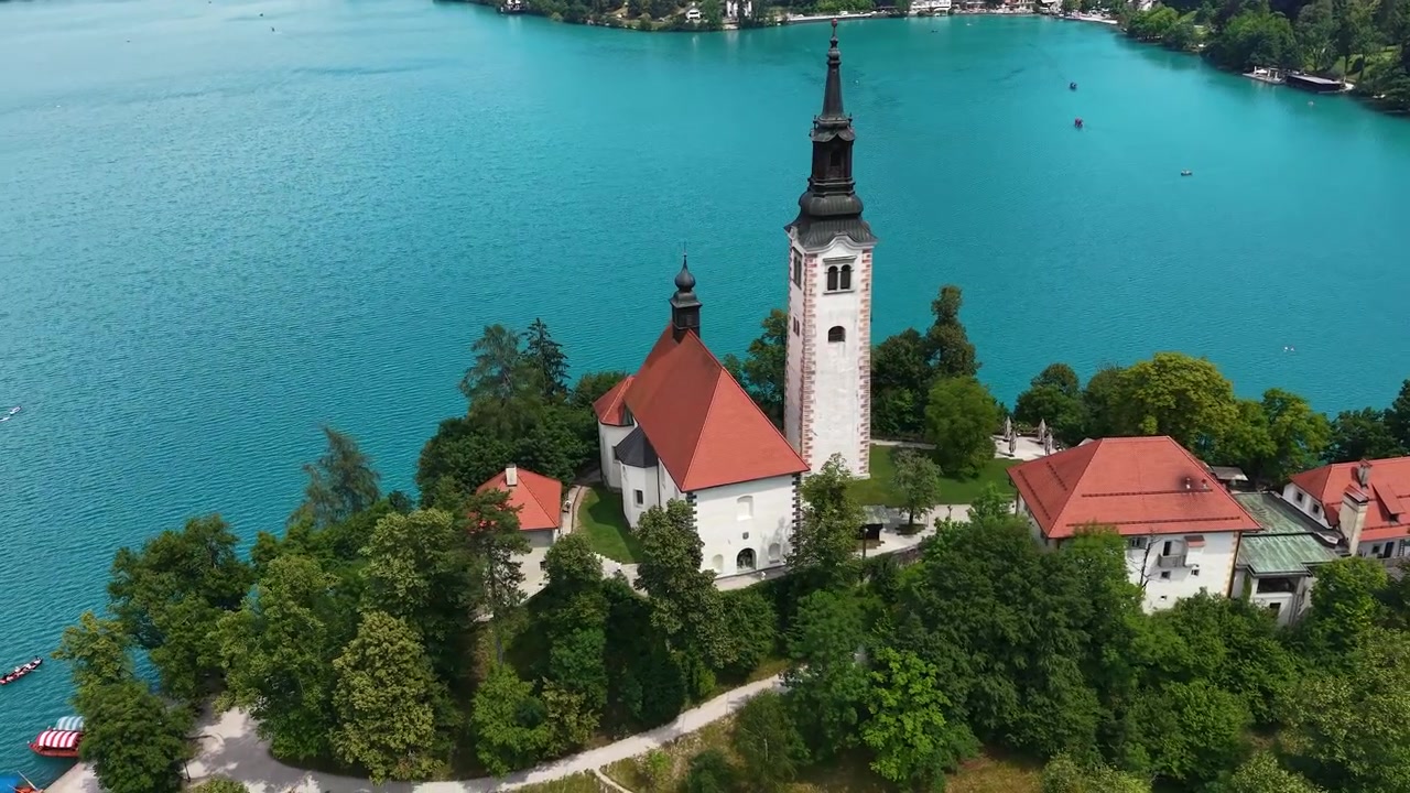 Ripresa drone di una chiesa cattolica su un'isola nel Lago di Bled, Slovenia, in una soleggiata giornata estiva.