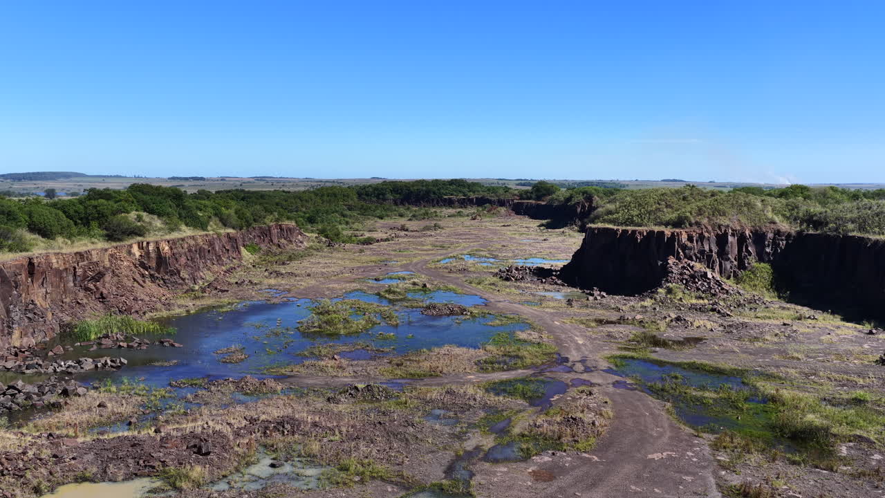 Ripresa aerea frontale che rivela una cava di pietra in Argentina con terreno esposto, sito di scavo e pozze d'acqua