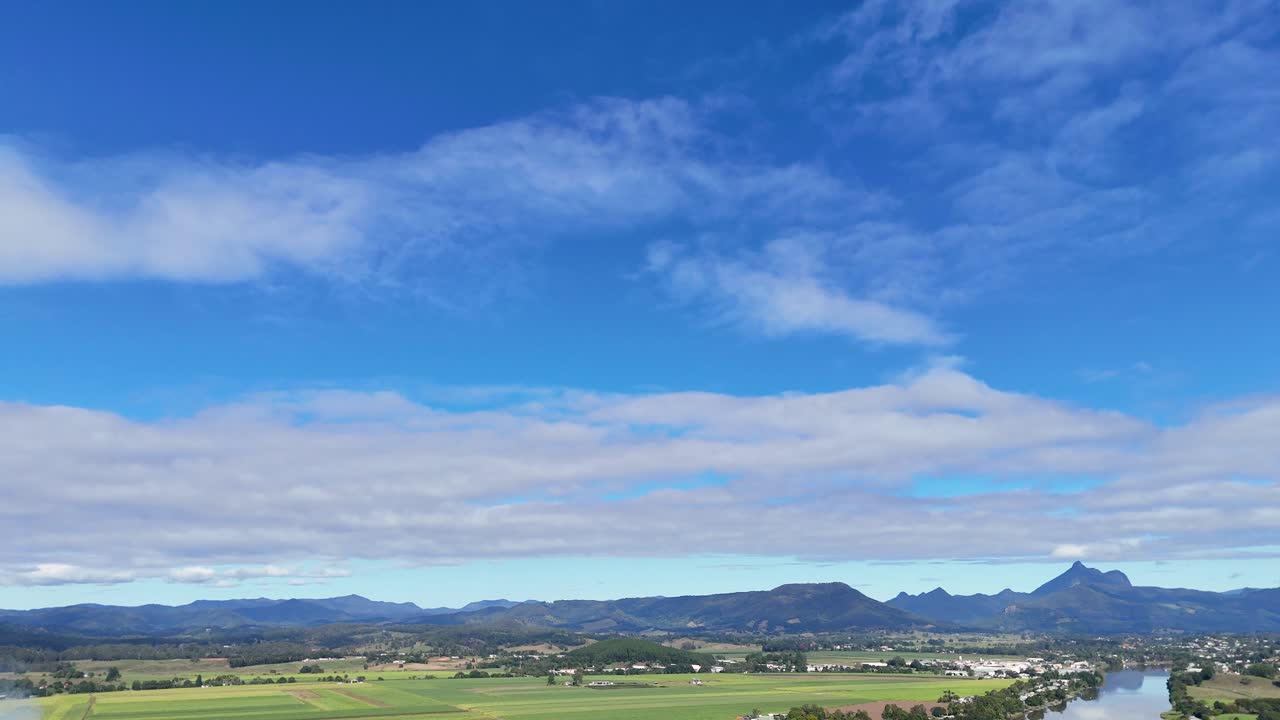 Drone footage captures smoke rising over a lush countryside, highlighting environmental impact under a clear blue sky