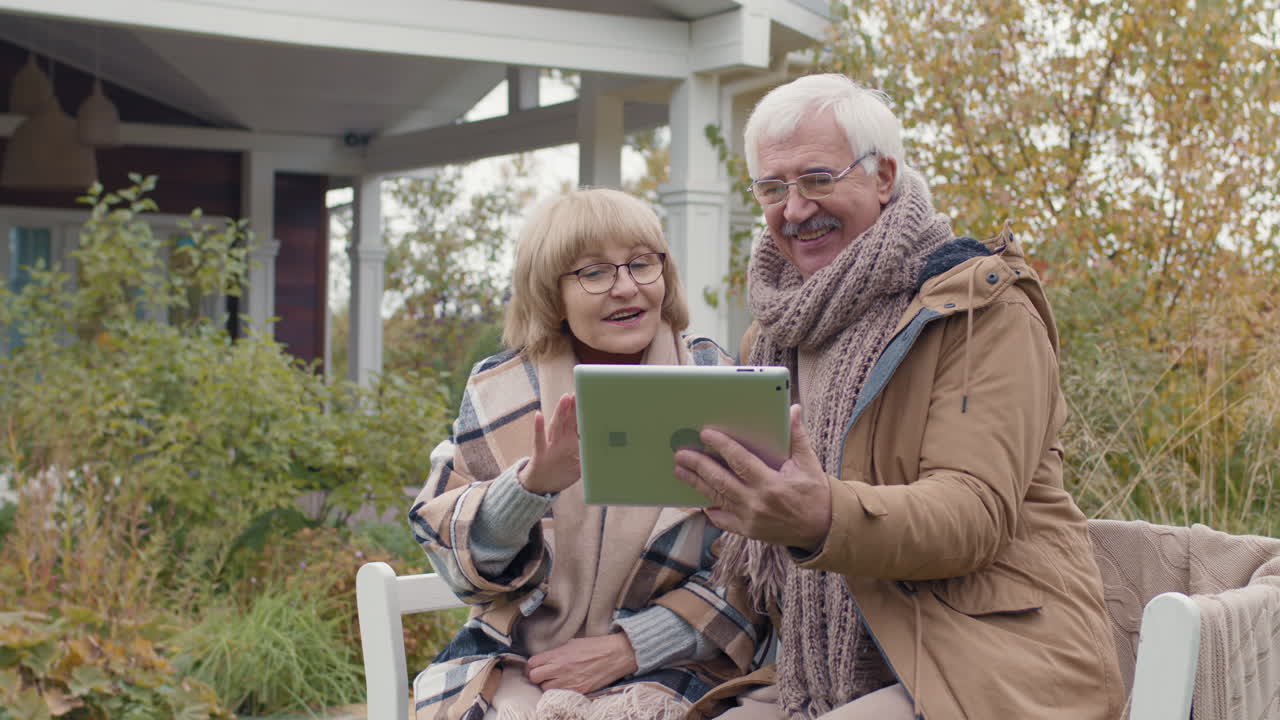 Senior couple using tablet outdoors in autumn