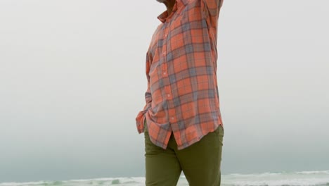 Vista-De-ángulo-Bajo-De-Un-Hombre-Afroamericano-Senior-Activo-Con-La-Mano-En-El-Bolsillo-Caminando-Por-La-Playa-4k