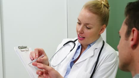 smiling female doctor explaining patient on clipboard