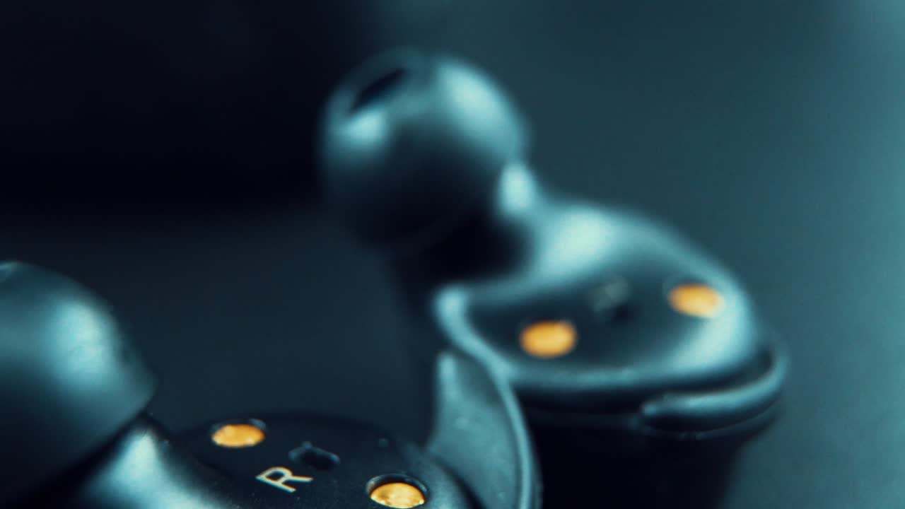 A cinematic macro shot of a wireless black earbuds earphones upside down, studio lighting, 120 fps, slow motion, Full HD