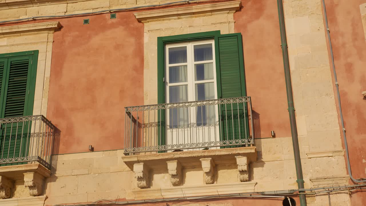 tomada en órbita a la derecha de un balcón histórico clásico en siracusa, sicilia, durante el amanecer de la hora dorada (sicilia, italia)