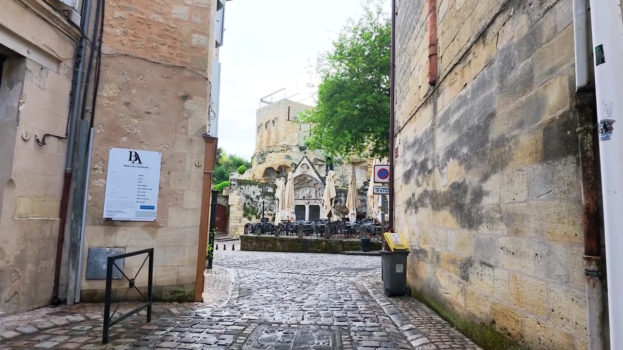 Una lenta carrellata in avanti attraverso un tranquillo vicolo medievale con edifici storici in pietra.