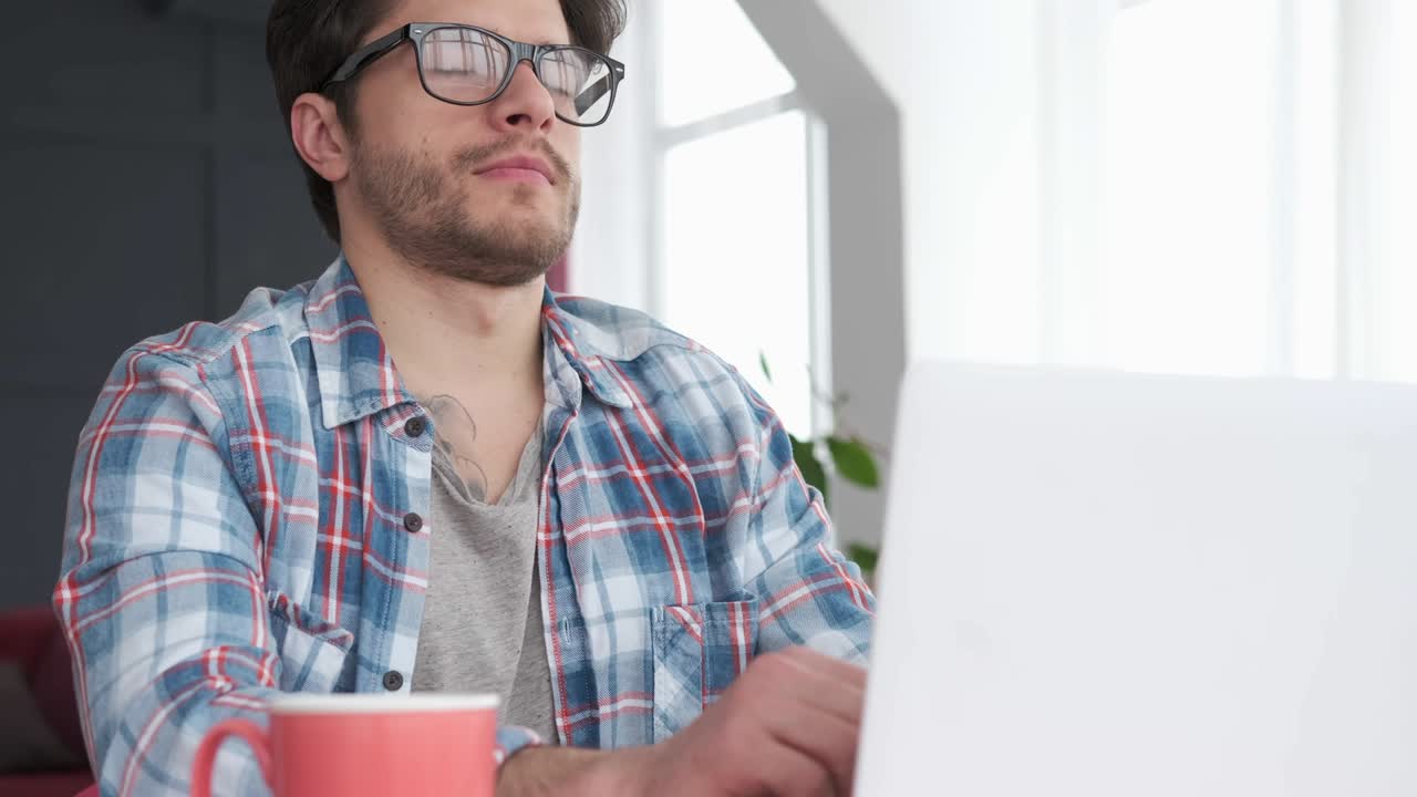 hombre bostezando mientras trabaja en la computadora portátil