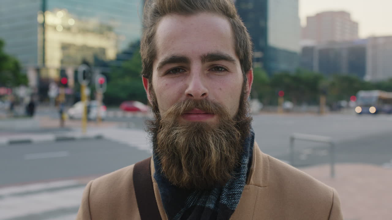 retrato de un atractivo joven barbudo hombre hipster que mira pensativo pensativo a la cámara en el fondo de la ciudad urbana puesta de sol
