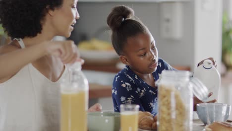 happy diverse mother with daughterhaving breakfast and talking in slow motion