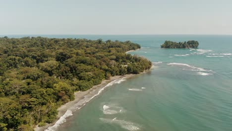 aerial view showing coastline of caribbean sea beside green deep rainforest and sandy beach - costa rica