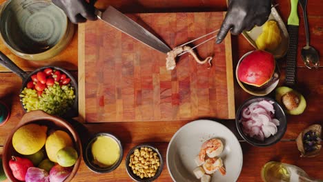 Table-top-view-of-a-faceless-professional-male-chef-cutting-octopus-tentacle-on-wooden-chopping-board,-preparing-seafood-gourmet,-restaurant-setting