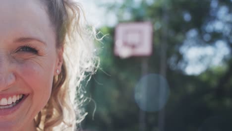 Half-portrait-of-happy-caucasian-female-basketball-player-on-sunny-court,-copy-space,-slow-motion