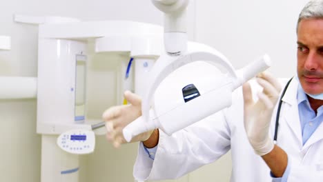 dentist in lab coat adjusting light