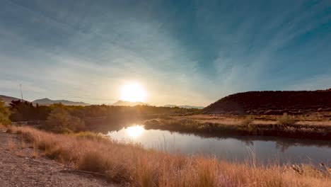 blue skies with wispy clouds as the morning sun rises and reflects off the river in this static time lapse