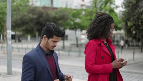 Mujer-Afroamericana-Y-Hombre-De-Raza-Mixta-Caminando,-Enviando-Mensajes-De-Texto-Por-Teléfono