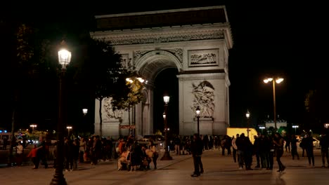 night view of paris with people walking on square near triumphal arch