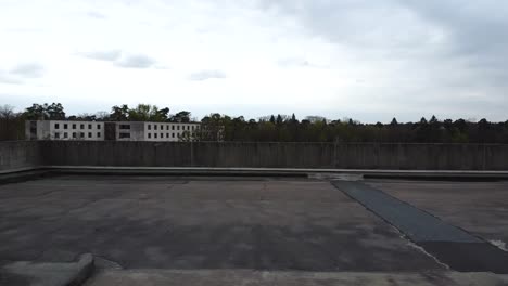 Drone-shot-over-a-old-parking-garage-ending-with-a-view-on-the-surrounding-landscape