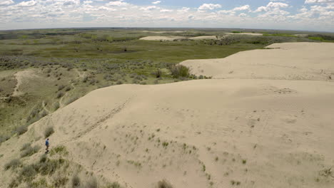 Un-Hombre-Solitario-Caminando-Por-Las-Colinas-En-Las-Grandes-Colinas-De-Arena-Durante-El-Día-En-El-Suroeste-De-Saskatchewan,-Canadá