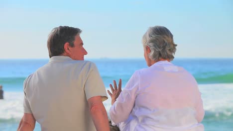 Mature-couple-sitting-talking-at-the-waters-edge