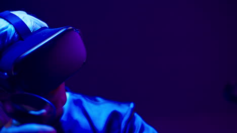 vr headset guy playing in neon light. man using futuristic technology helmet