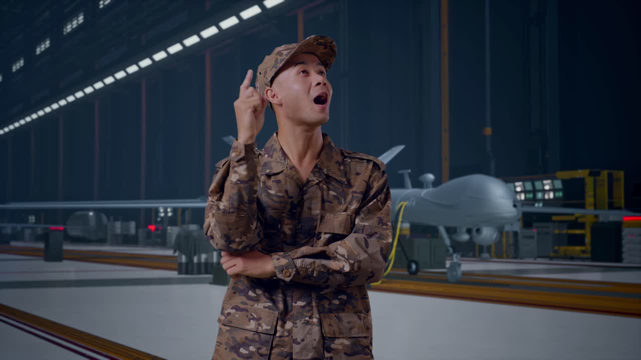 Asian Man Soldier Thinking And Looking Around Then Raising His Index Finger While Standing With Modern Military Drone In Maintenance Hangar