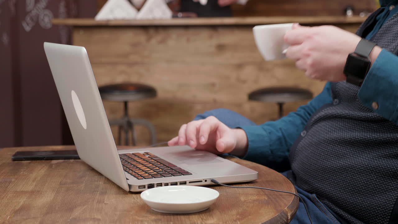 Man working on laptop in cafe with coffee