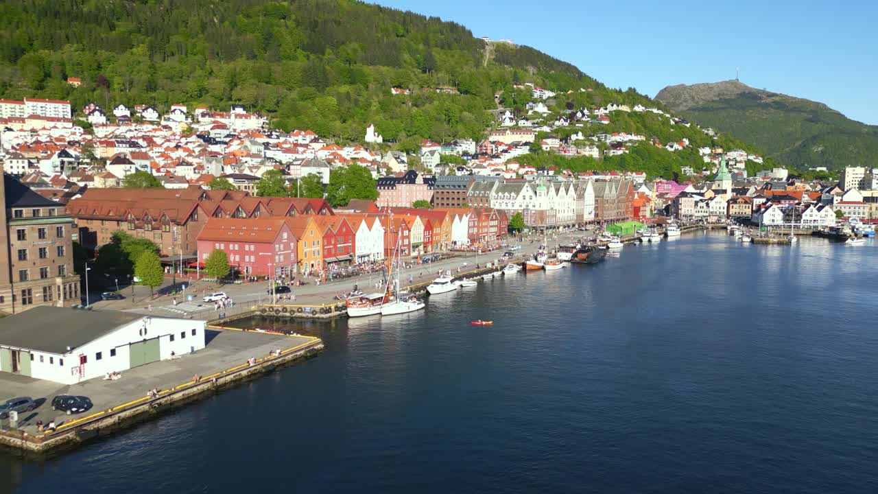 Luftfoto af Bryggen kaj i Bergen, Norge, der viser dens UNESCO-listede træbygninger langs havnefronten, med frodige grønne bjerge i baggrunden
