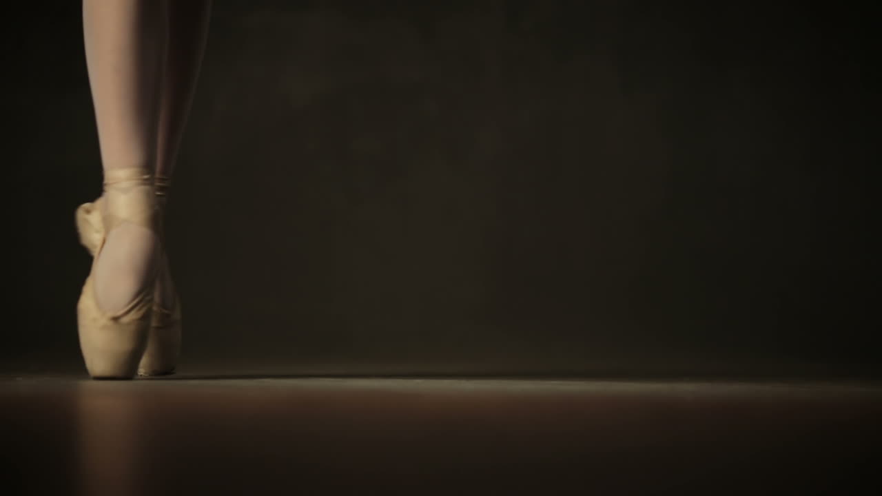 Young incredibly beautiful girl ballerina posing and dancing in a black studio