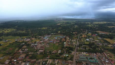 aerial view of a town on the countryside of kenya, africa, forest fire background - rising, drone shot