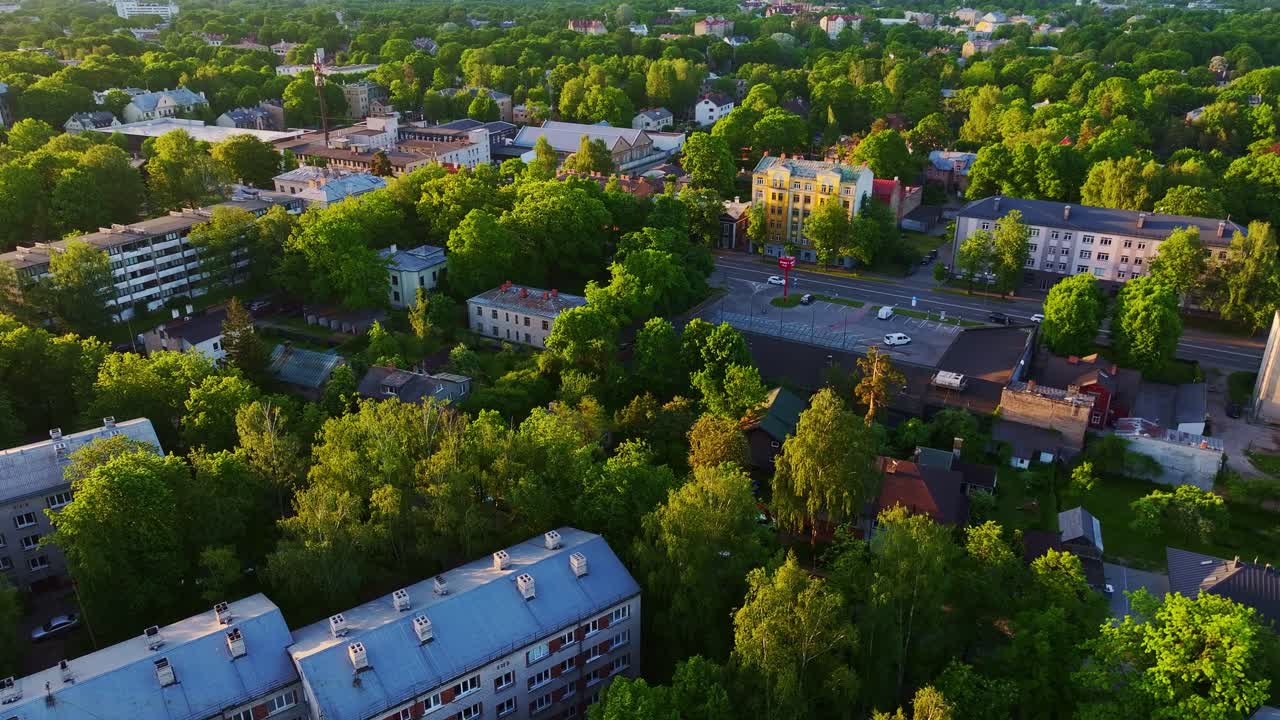 La luce dorata dell'alba illumina tetti grigi di appartamenti e alberi verdi a Riga.