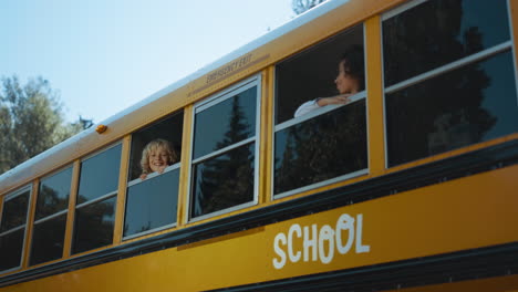 schoolchildren looking out bus window in morning. students standing in schoolbus