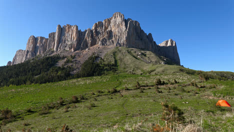 alto castillo de roca expuesto en la cordillera del cáucaso de kavkaz con tienda de mochila naranja