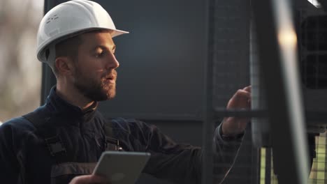 portrait of a young male electrician at the reception of the switchboard with a tablet