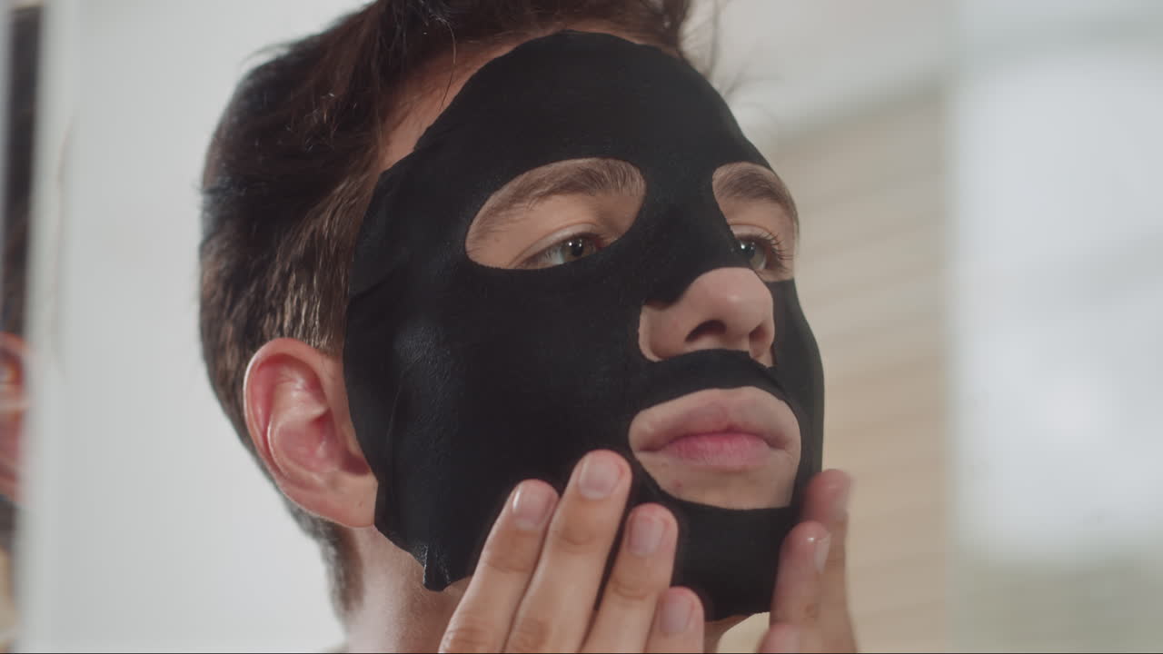 Man Using Hydrating Black Mask during Skin Care Procedure