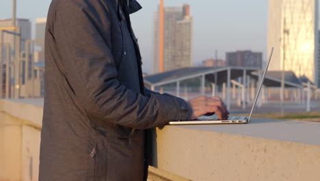 Closeup-on-male-hacker-typing-security-code-on-laptop-at-Barcelona-waterfront-business-district