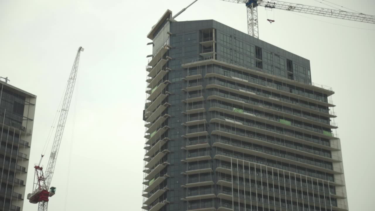 Costruzione di edificio urbano con gru sulla sommità e cielo grigio sullo sfondo - ripresa dall'alto verso il basso