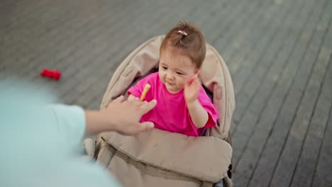 adorable baby girl in a stroller smiling and reaching for food