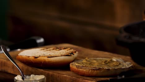 mustard and honey sauce for home made burger in the kitchen. stock footage. close up of male cook hands adding mustard on a burger bun