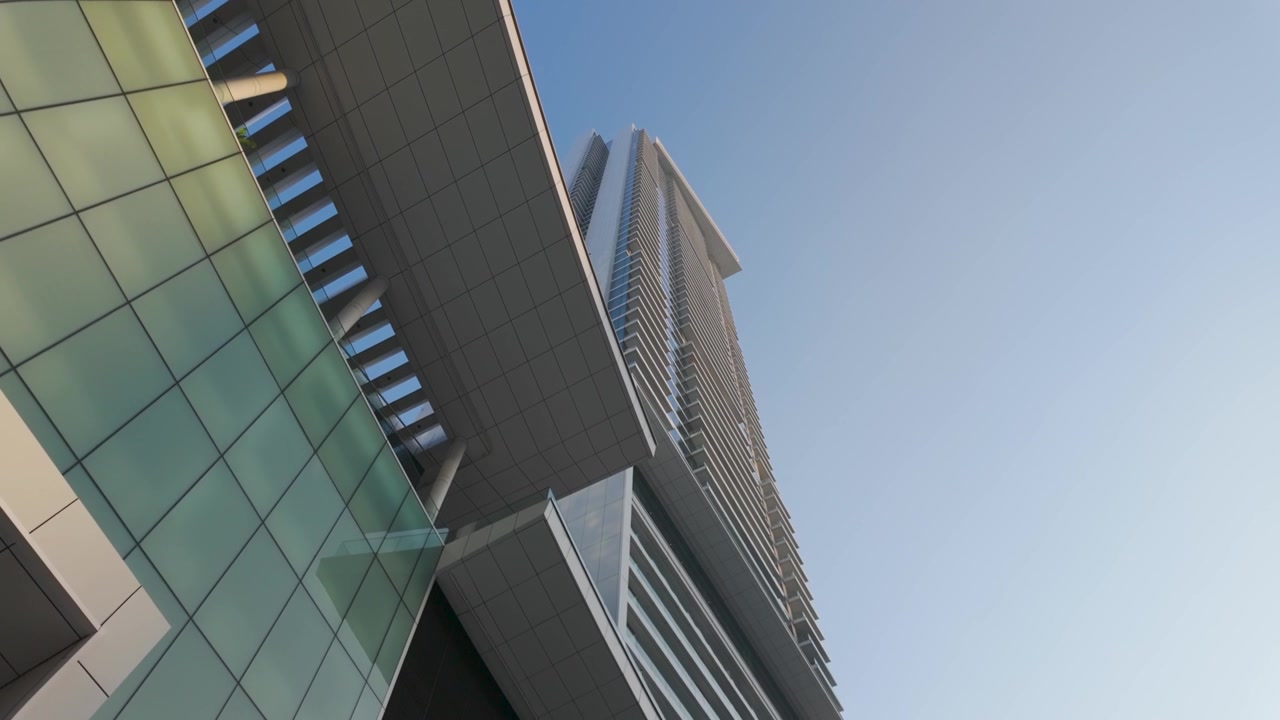 Cobertura de vidro verde e quebra-sol de ripas de uma entrada de shopping se estendem abaixo de uma torre residencial que se eleva em um céu azul claro.