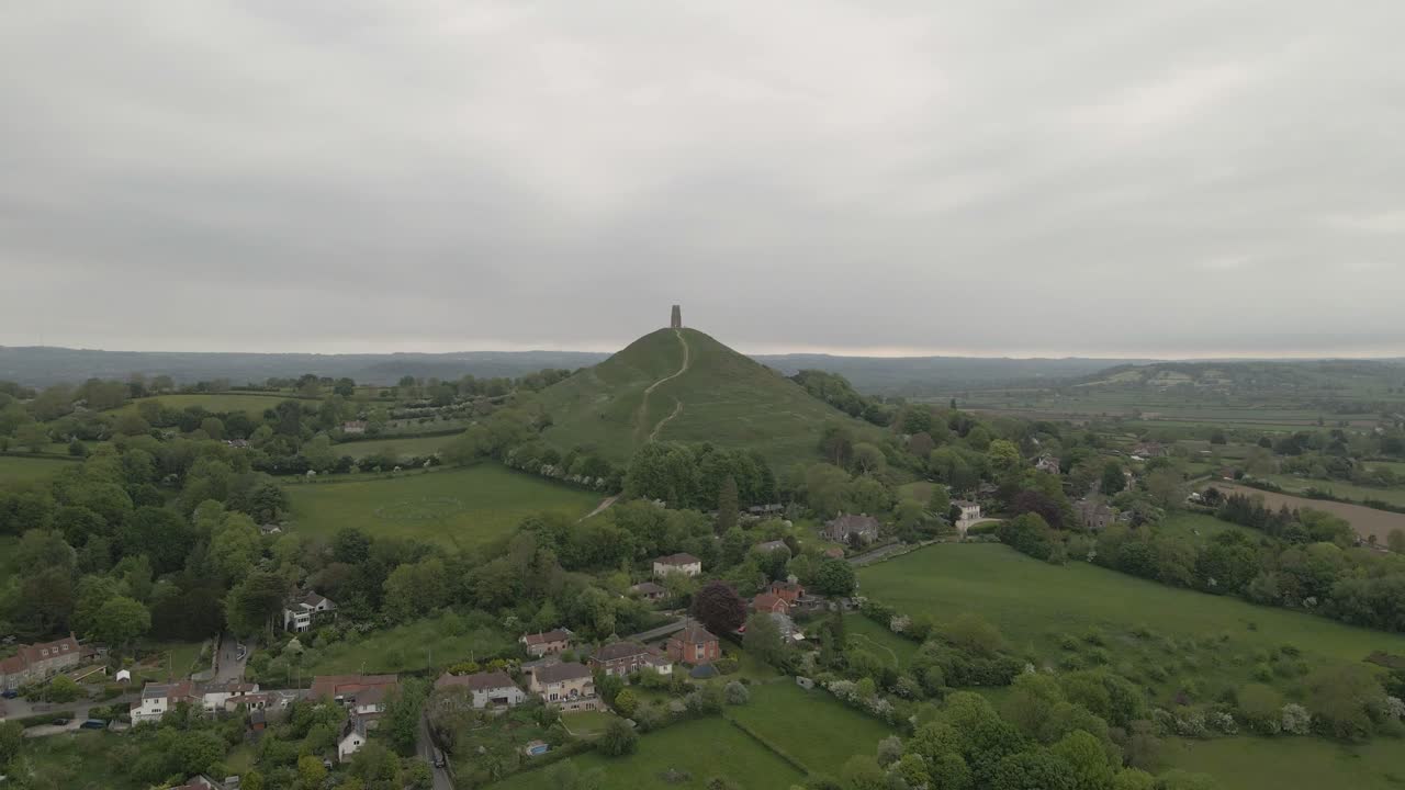 Aerial view of Glastonbury, drone moving forward side showing the tower and the extension of Glastonbury, drone flying over the green fields . 4K, 60fps.
