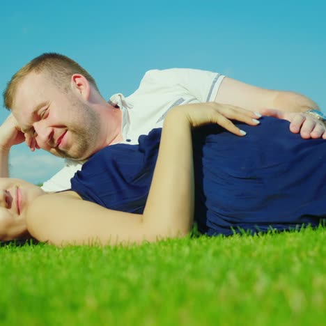 Husband-With-A-Pregnant-Wife-Is-Lying-On-The-Green-Grass