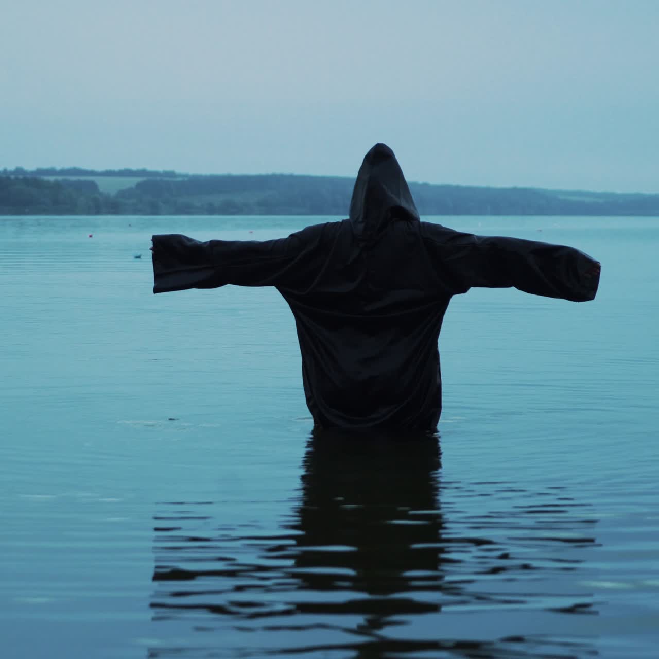 Female figure in a black robe in the river. Divination in the night of Halloween.