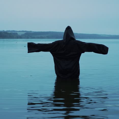 female figure in a black robe in the river. divination in the night of halloween.