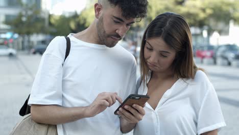 pareja joven enfocada mirando el teléfono inteligente