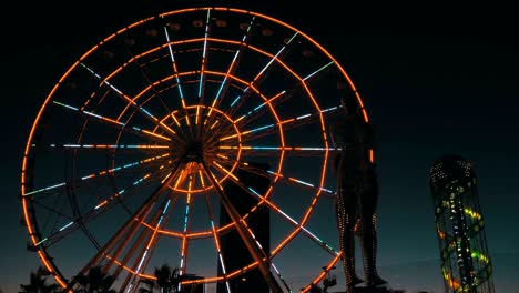 estatua de ali y nino en una rueda de ferris de fondo por la noche en el terraplén de batumi, georgia