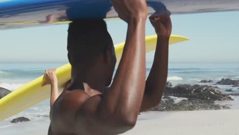 pareja afroamericana con tablas de surf en sus cabezas