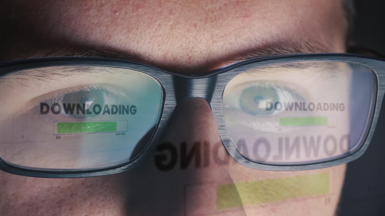 la pantalla de la computadora se refleja en las gafas del hombre - se concede acceso y se inicia la descarga - primer plano