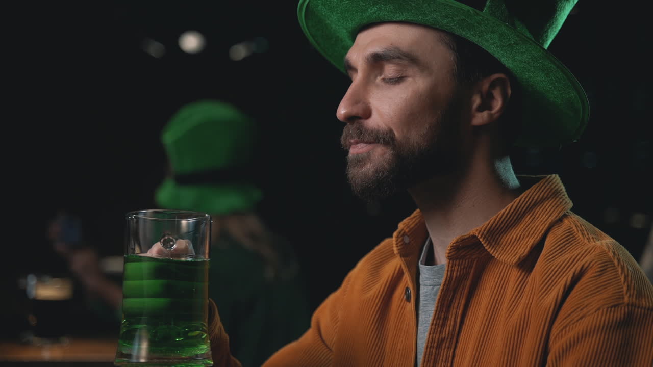 Portrait of a young man drinking a green beer mug. Celebrating Saint Patrick's Day in a pub.